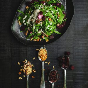 Gourmet salad with assorted nuts and herbs presented in a stylish flat lay.