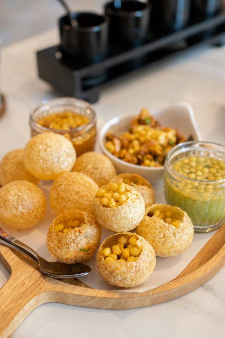 Delicious Indian street food Pani Puri served with spicy water and fillings on a wooden tray.
