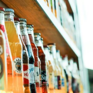 Vibrant soda bottles lined on a wooden shelf, ideal for stores or beverage displays.