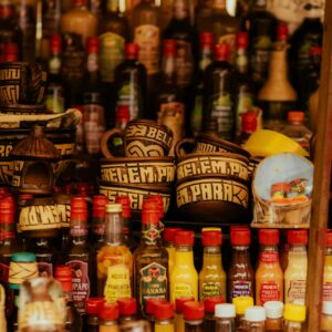Vibrant market stall displaying various bottles of sauces and spices in colorful containers.