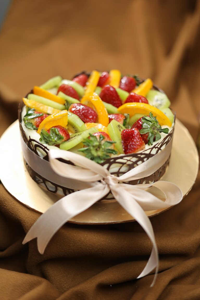 A beautifully decorated fruit-topped chocolate cream cake, perfect for dessert lovers.