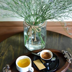 A cozy indoor setup featuring espresso and tea on a tray with a decorative vase.