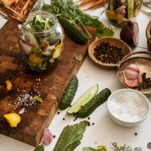 Top view of fresh ingredients for pickling cucumbers with herbs and spices on a wooden cutting board.